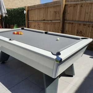 Outdoor white Cry Wolf pool table set up with balls on a patio area.