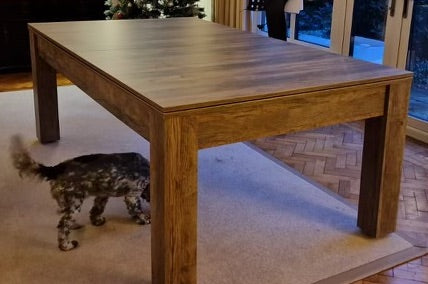 7' Santa Fe Walnut Rosetta dining table with a modern wood finish, shown in a living room setting.